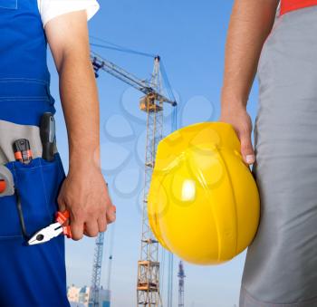 Royalty Free Photo of Workers Holding Tools With a Building in the Background