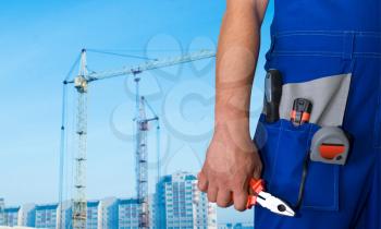 Royalty Free Photo of a Worker Holding a Tool With a Building in the Background