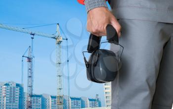 Royalty Free Photo of a Man Holding Protective Headphones at a Building Site
