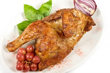 Half roasted chicken closeup with grape and greens on a white