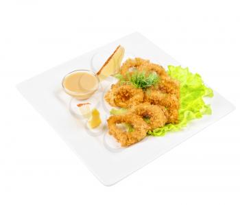 Deep-fried squid with salad leaves, sauce, green and lemon on a white background
