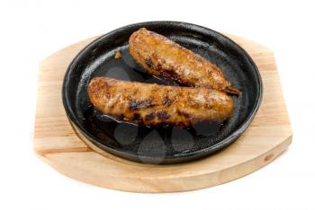 Roast sausages at pan with sauce on a white background