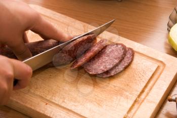 Royalty Free Photo of a Hand Cutting up Salami