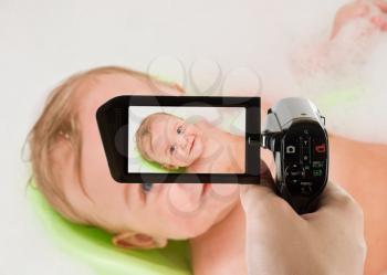 Royalty Free Photo of a Woman Recording Her Baby Taking a Bath