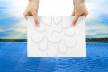 Royalty Free Photo of a Person Holding Paper Over Water