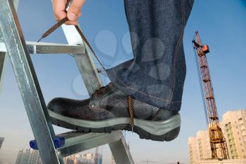 Royalty Free Photo of a Repairman Tying His Shoelace on a Ladder