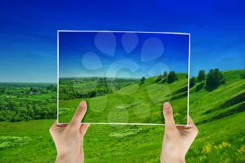 Royalty Free Photo of Hands Holding a Photo of a Hilly Landscape