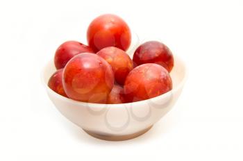 Plums at bowl on white background