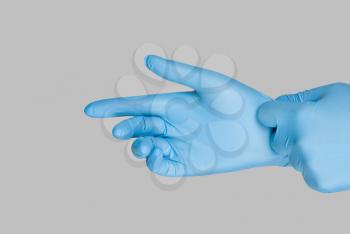 Blue gloves on a hand on a grey background