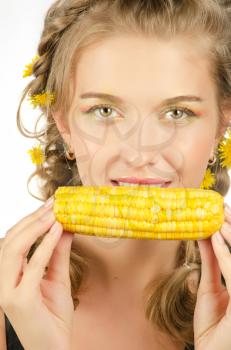 Close-up portrait of young beauty woman eating corn-cob on a white