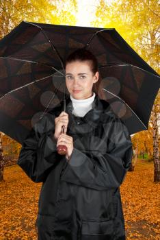 woman in rain coat with umbrella walking at autumn forest