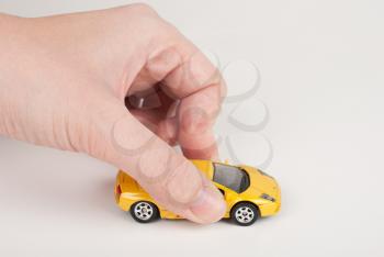 Female hand playing with toy yellow car.