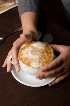 Hands holding cup of cappuccino