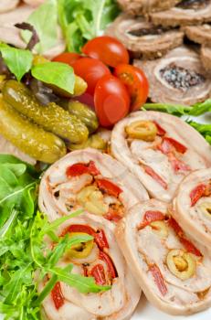 Cutting meat tenderloin stuffed with prune and peper and olive with lettuce, tomatoes, cucumbers and ruccola