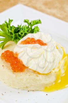 poached eggs in a nest of mashed potatoes with greens and caviar