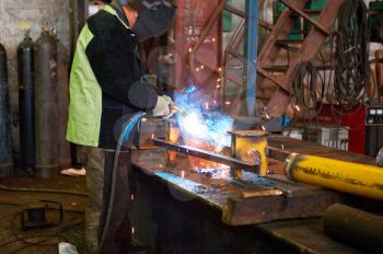 worker welding metal with sparks at factory