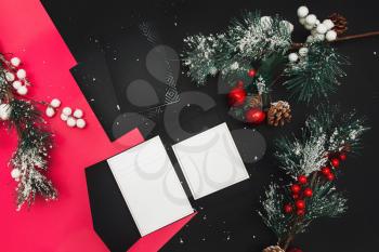 Christmas minimal mockup - red xmas balland firtree on black background. Horizontal composition with empty paper blank. Flat lay, top view.