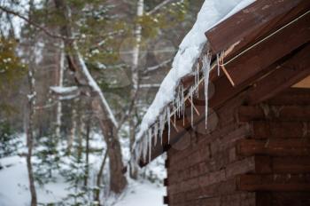 Closeup photo of the Icicles hang from the roof of wooden house