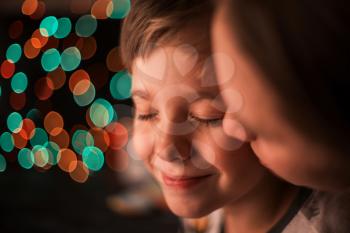 Closeup portrait of boy and his mother on dark bokeh background