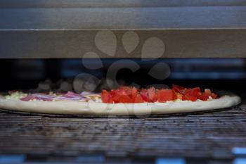 Preparing pizza in oven at restaurant kitchen