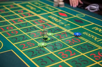 Casino, gambling and entertainment concept - green roulette table with colored chips ready to play