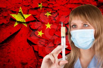 Female doctor with medical mask on China flag background. Concept of corona virus.