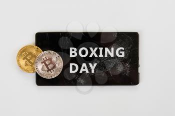 Bitcoin coins on the broken phone with Boxing day sign