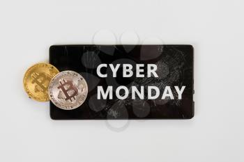 Bitcoin coins on the broken phone with Cyber Monday sign