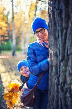 Beauty woman and her son at autumn park in sunny beauty day