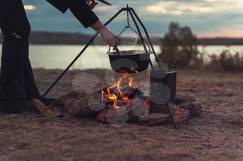 Preparing food on campfire in wild camping, resting on the nature