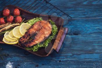 Grilled salmon steak with vegetable on a blue wooden background