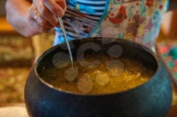 Pouring soup from retro russian authenticity cast-iron dishes