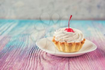 Tasty mini cake with cherry on a color gradient background
