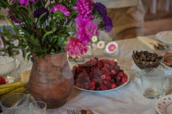 Decorated rustic table with flowers and plate of raspberries