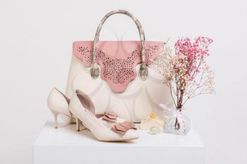 Female handbag, shoes and bouquet of dried flowers on white background