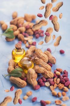 Natural peanuts with oil in a glass jar on the blue concrete background