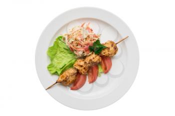 Delicious chicken shish kebab on skewers with vegetables at plate isolated on a white background