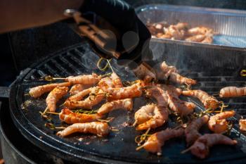 A professional cook prepares shrimps on the grill outdoor, food or catering concept