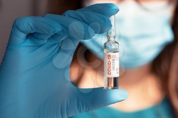 Coronavirus vaccine concept: New covid-19 vaccine with 90 percent efficiency in hand with blue protective gloves.