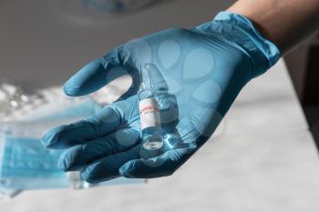 Coronavirus vaccine concept: covid-19 vaccine in doctor hand with blue protective gloves.