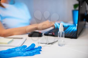 Woman working with notebook. Protective mask and Sanitizer spray on the working place