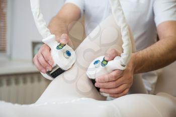 Procedure laser lipolysis of the woman hips in a beauty center.