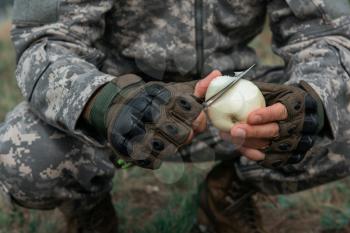 A man with a knife and the apple in the forest. Travel or military concept