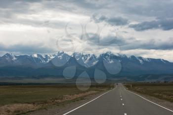 Empty route in Altai mountains on snowly peaks background
