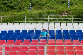 Lonely boy on the empty stadium outdoor. Empty tribune due to pandemic Covid-19. Concept of pandemic life , empty stadiums, distance from viewers, safety.