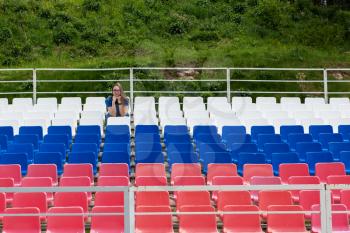 Lonely woman on the empty stadium outdoor. Empty tribune due to pandemic Covid-19. Concept of pandemic life , empty stadiums, distance from viewers, safety.