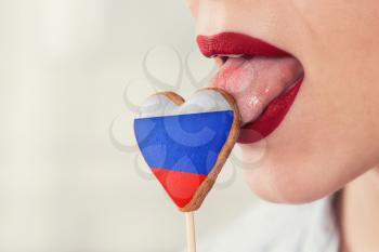 Closeup photo of the woman lips and cookie hearts with flag of Russia