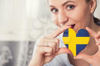 Young woman with gingerbread heart cookies with flag of Sweden