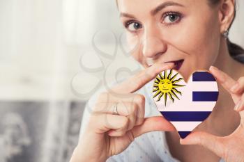 Young woman with gingerbread heart cookies with flag of Uruguay