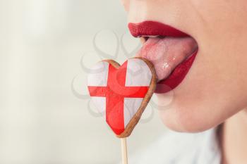 Closeup photo of the woman lips and cookie hearts with flag of England